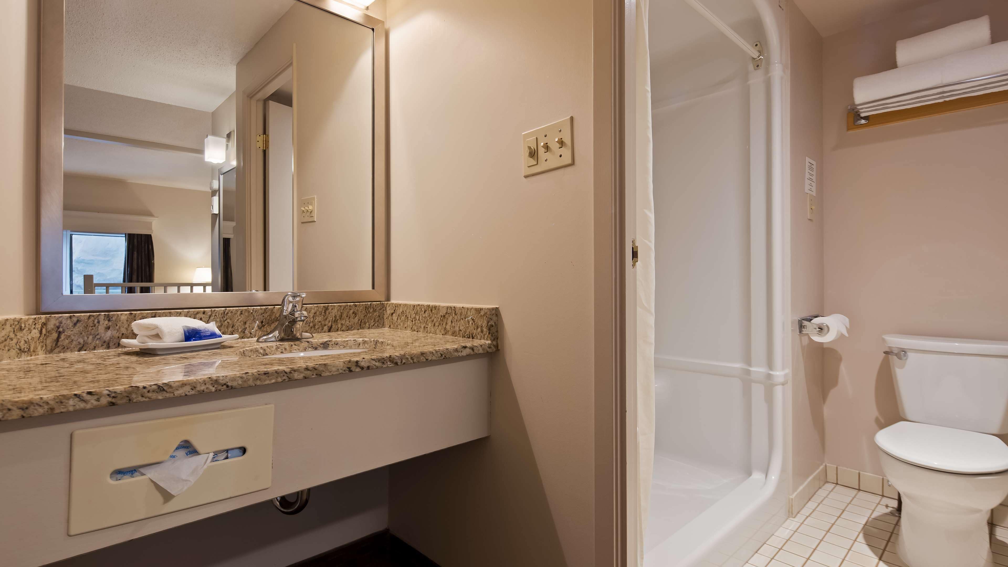Ein Badezimmer mit Waschbecken, Spiegel, Handtuchhalter und Toilette.