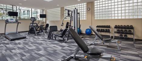 Un gimnasio con cintas de correr, máquinas de pesas y mancuernas.