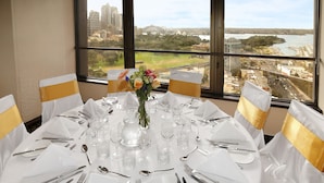 A table set for six with a view of a cityscape through large windows. - The Sydney Boulevard Hotel by Accor (Woolloomooloo)