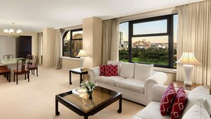 A hotel room with a dining area, a sofa, a coffee table, and a view of a cityscape. - The Sydney Boulevard Hotel by Accor (Woolloomooloo)