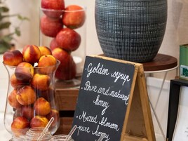 A clear glass bowl filled with peaches, a blackboard with text, and a large ceramic bowl on a table.