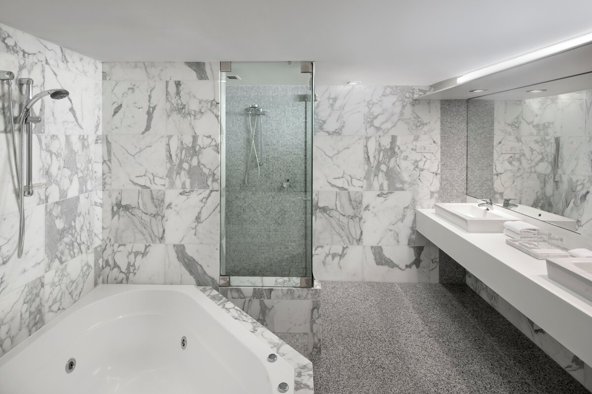 A modern bathroom with a glass-enclosed shower, a freestanding bathtub, and a vanity with a mirror.