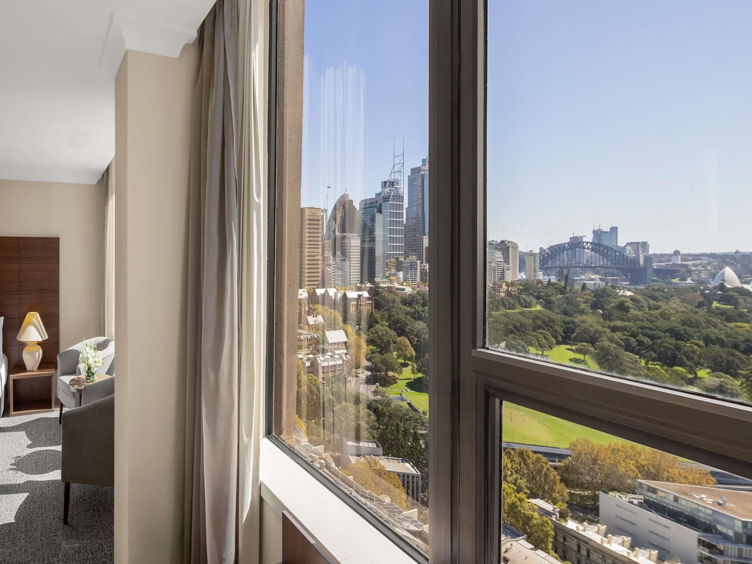 A room with a large window offering a view of a cityscape, including a bridge and skyscrapers.