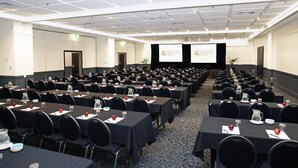 A conference room with rows of tables, each with nameplates, water pitchers, and apples. - The Sydney Boulevard Hotel by Accor (Woolloomooloo)