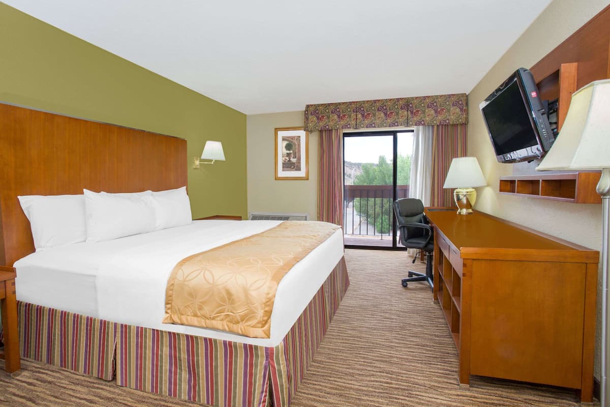 A hotel room with a large bed, a desk, a television, and a window with curtains.