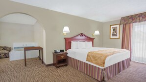 Una habitación de hotel con una cama grande, una mesita de noche, un escritorio y una silla.