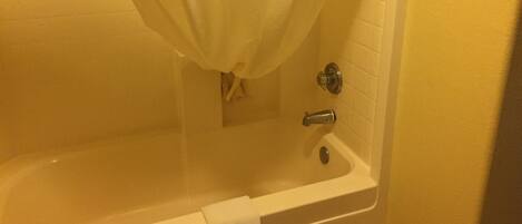 Une baignoire avec un rideau de douche, une serviette accrochée sur le côté et un robinet.