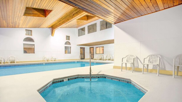 Una piscina interior con techo de madera y paredes blancas.
