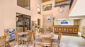 Un vestíbulo de hotel con mostrador de recepción, muebles de madera y un amplio ventanal.