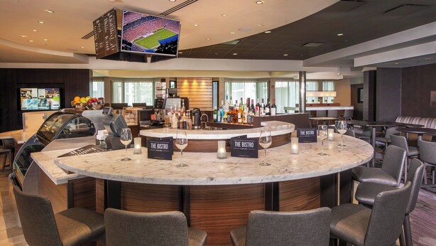 Eine moderne Bar mit Marmorplatte, verschiedenen Sitzgelegenheiten und einem an der Decke befestigten Fernseher.