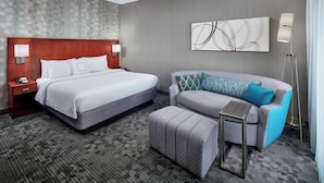 Ein Hotelzimmer mit Bett, einer Couch, einem kleinen Tisch und einer Stehlampe.