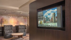 Eine moderne Hotelhalle mit einem großen digitalen Bildschirm, der eine Stadtansicht zeigt, bequemen Sitzgelegenheiten und einem klaren, zeitgenössischen Design.