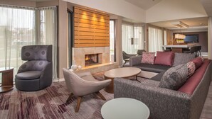 Ein modernes Wohnzimmer mit Kamin, einer Sofagarnitur, einem runden Couchtisch und einem Fernseher im Hintergrund.
