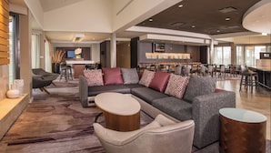Eine moderne Hotelhalle mit Ecksofa, Barbereich und Essbereich.