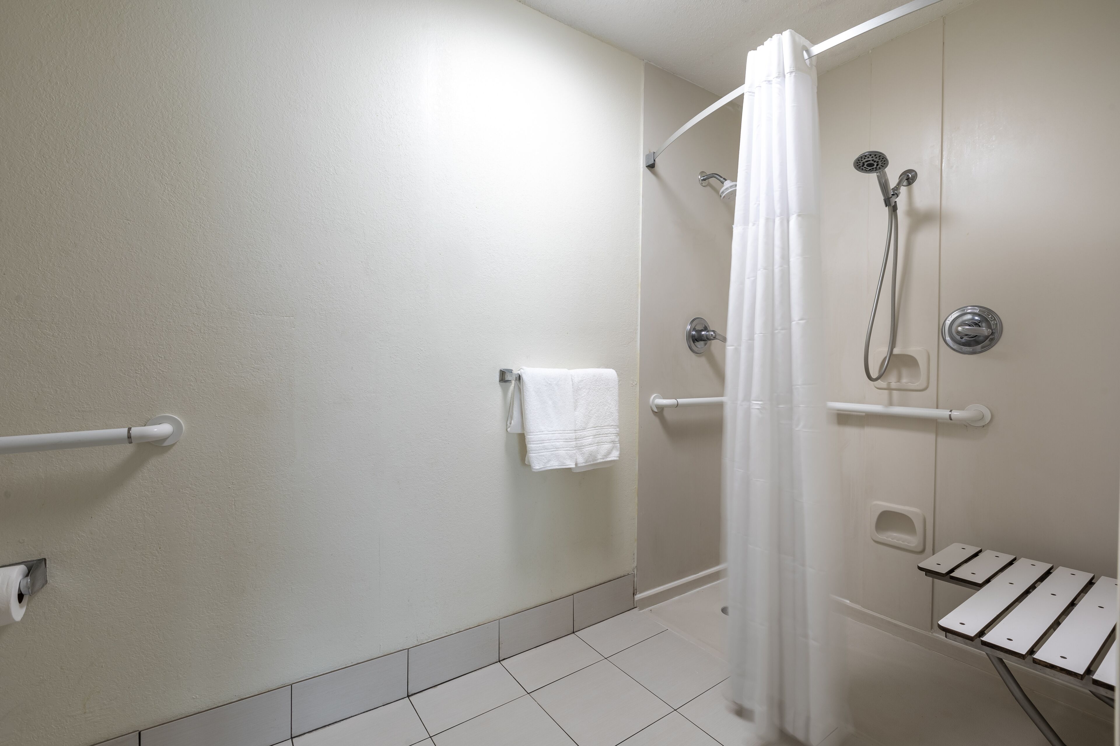 A bathroom with a shower, a toilet, and a towel rack.