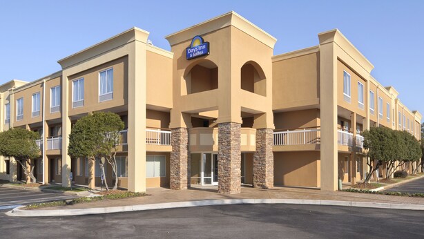 A Days Inn & Suites building with a beige facade, multiple balconies, and a clear sky. - Days Inn by Wyndham Greenville (Greenville)