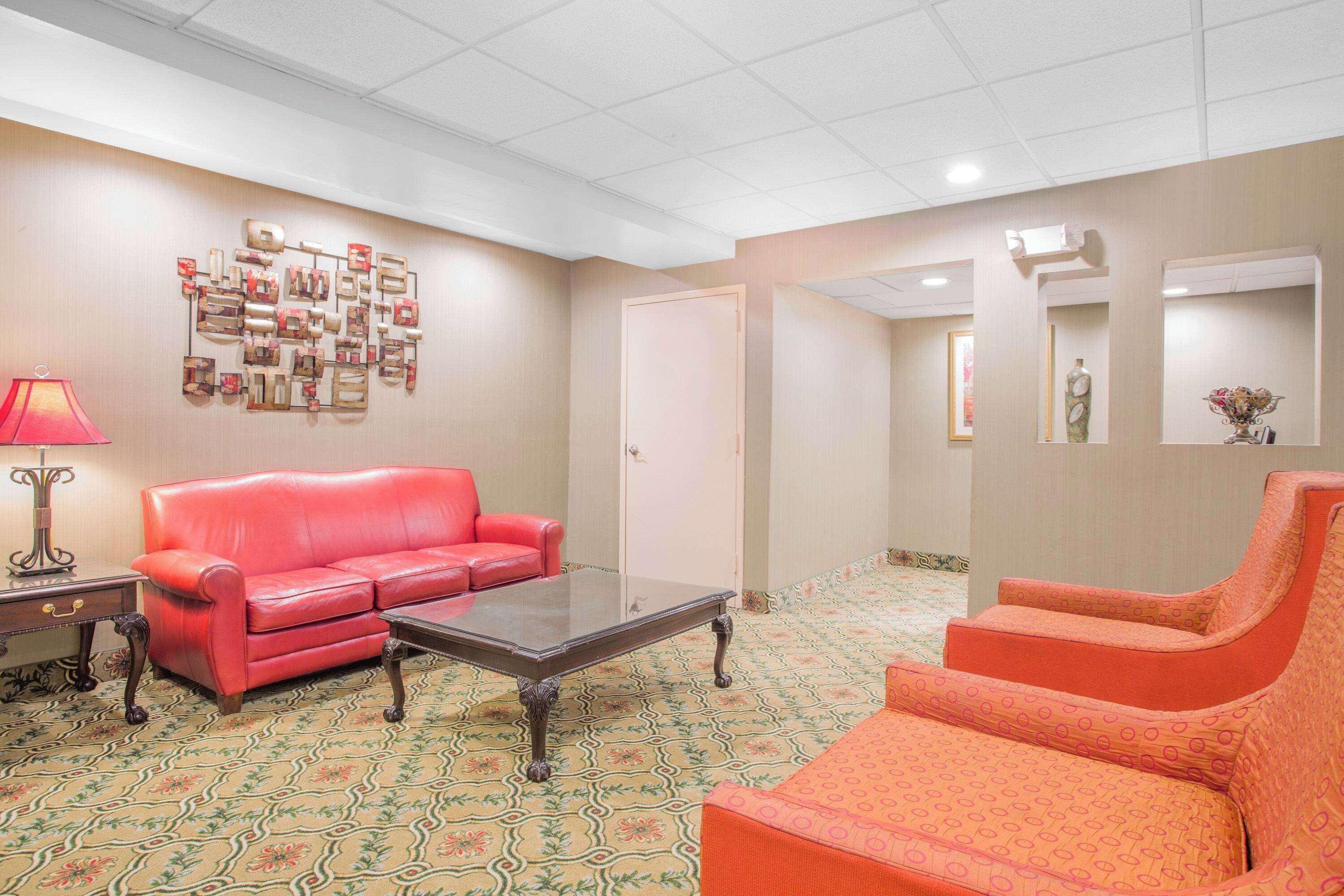 Una habitación con un sofá rojo, un sillón a juego, una mesita de centro, una alfombra estampada y una obra de arte en la pared.
