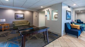 A hotel lobby with a sofa, a table, a bench, and a reception desk. - Days Inn by Wyndham Greenville (Greenville)