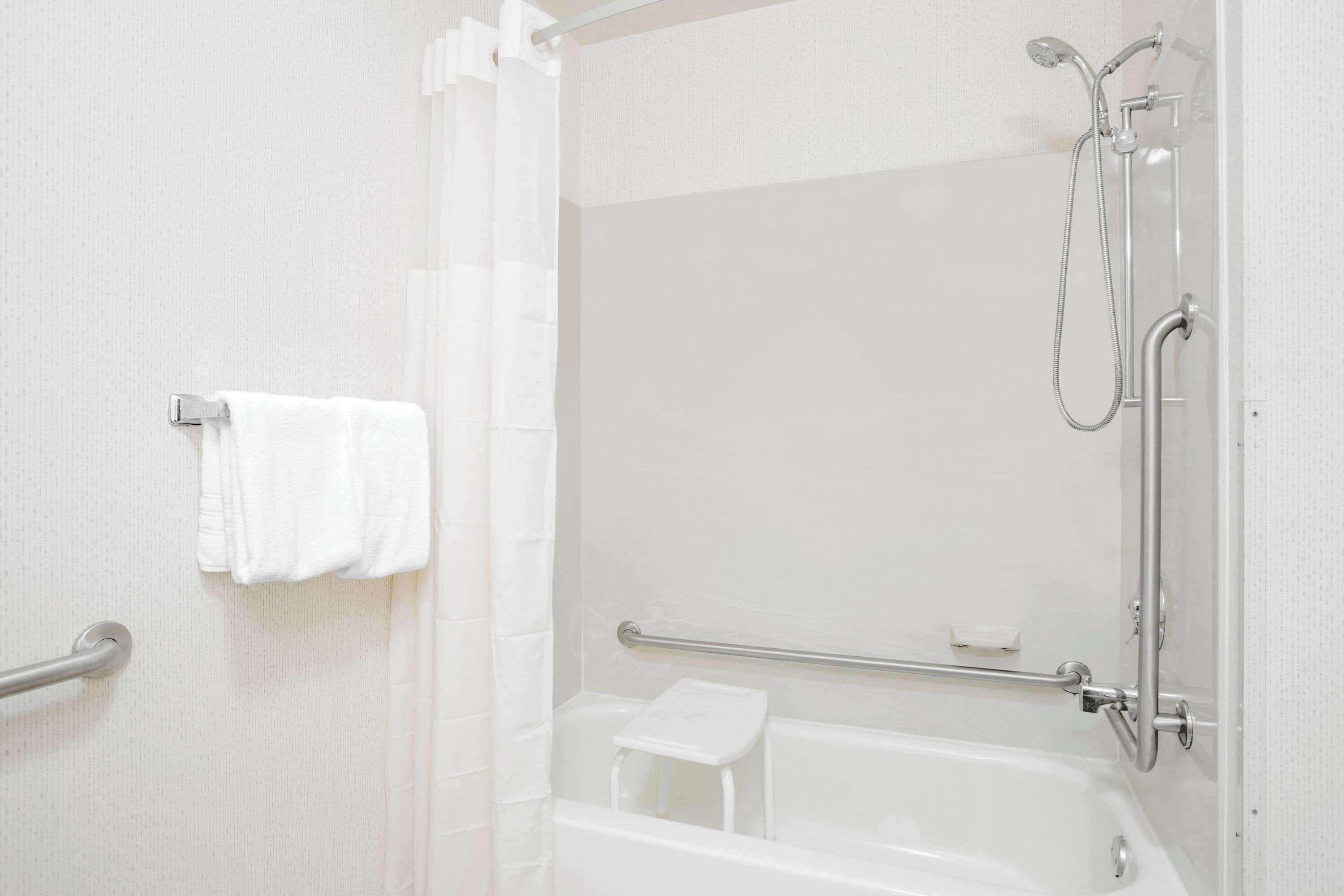 Ein Badezimmer mit Badewanne, Dusche und Haltegriff.