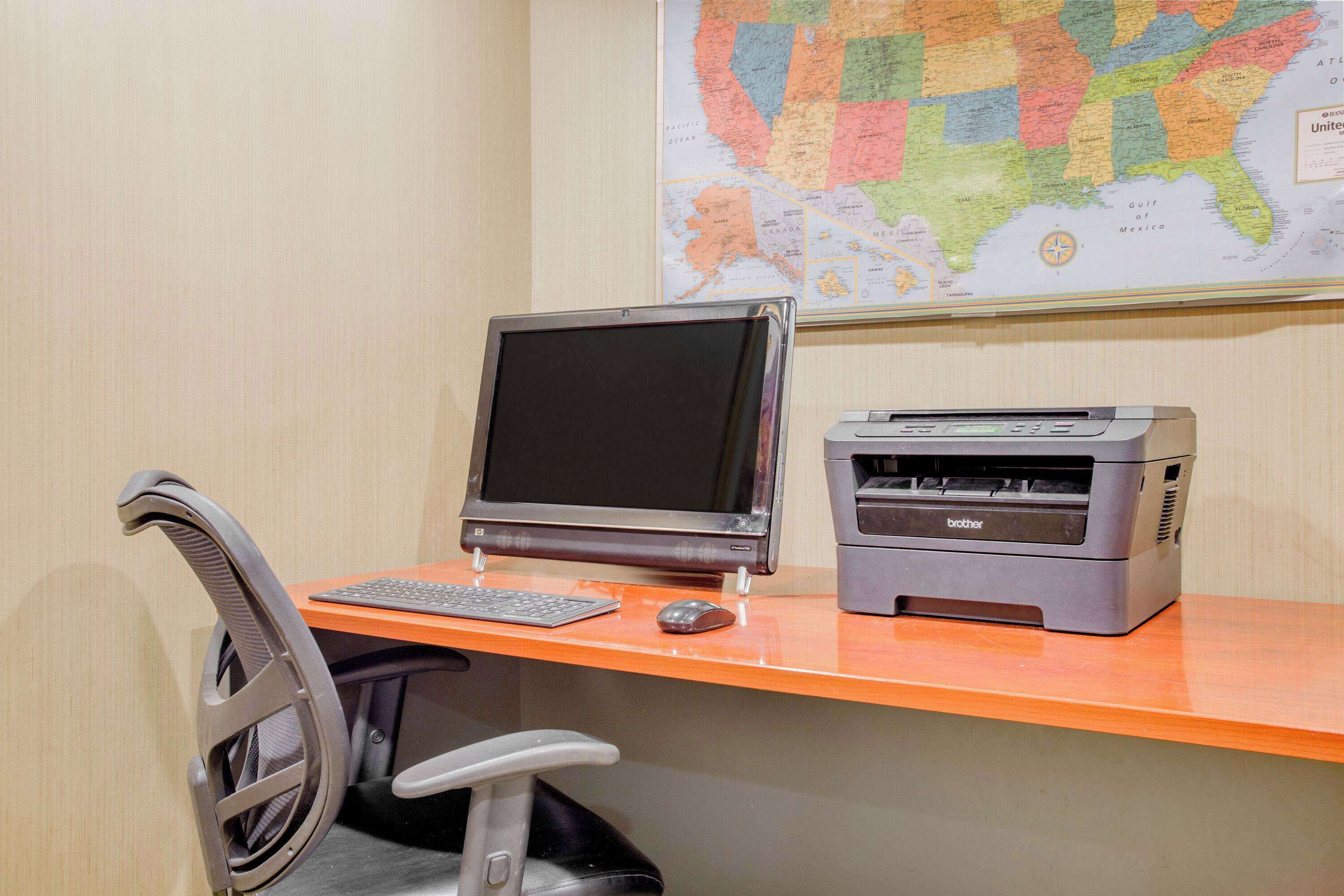 A computer desk with a monitor, keyboard, mouse, and printer.