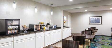 A hotel dining area with a buffet, seating, and a framed picture on the wall.