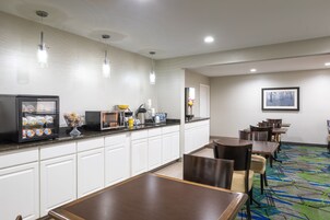 Un comedor de hotel con bufé, asientos y un cuadro en la pared.
