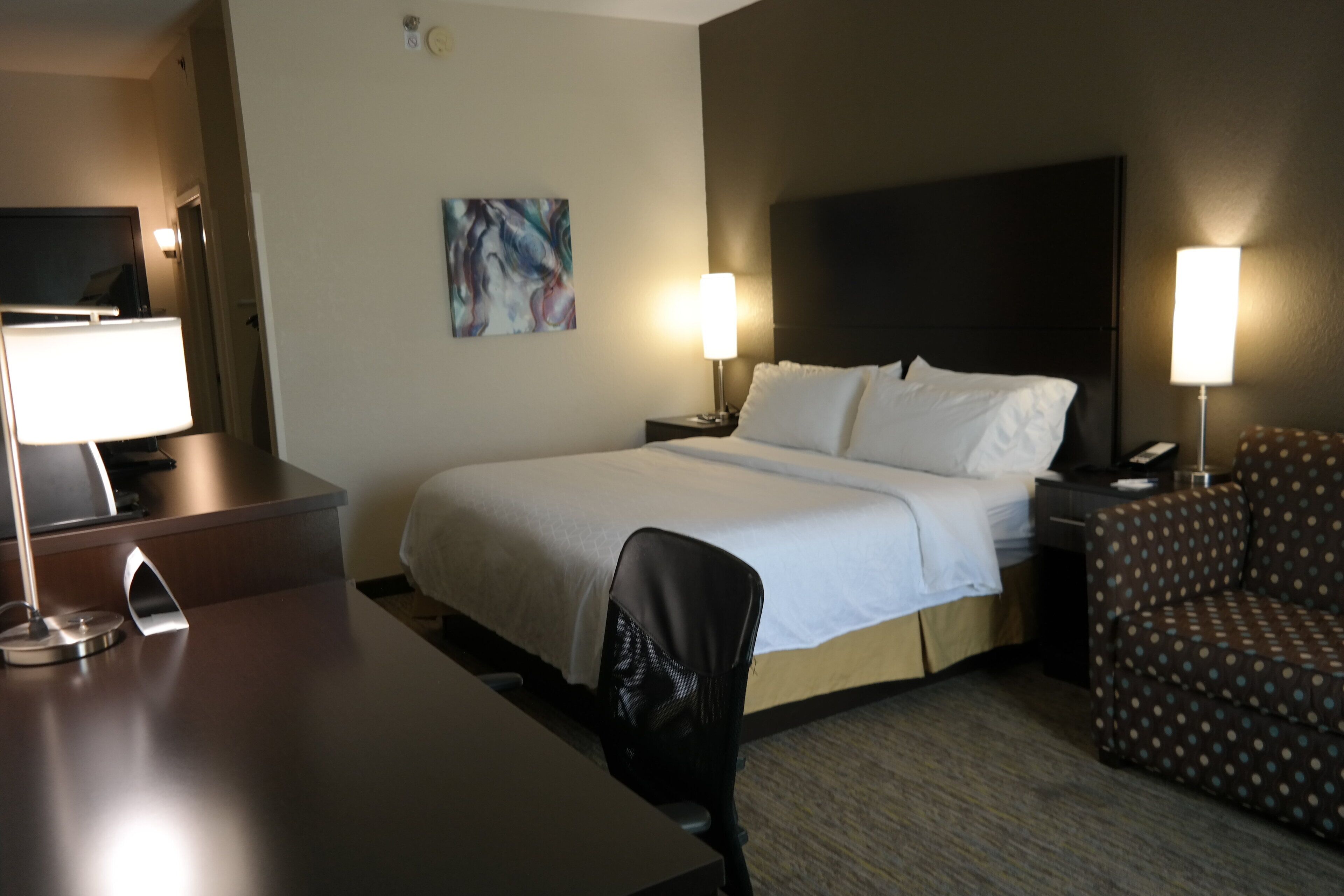 Une chambre d’hôtel avec un lit, un bureau, une chaise et un téléviseur.