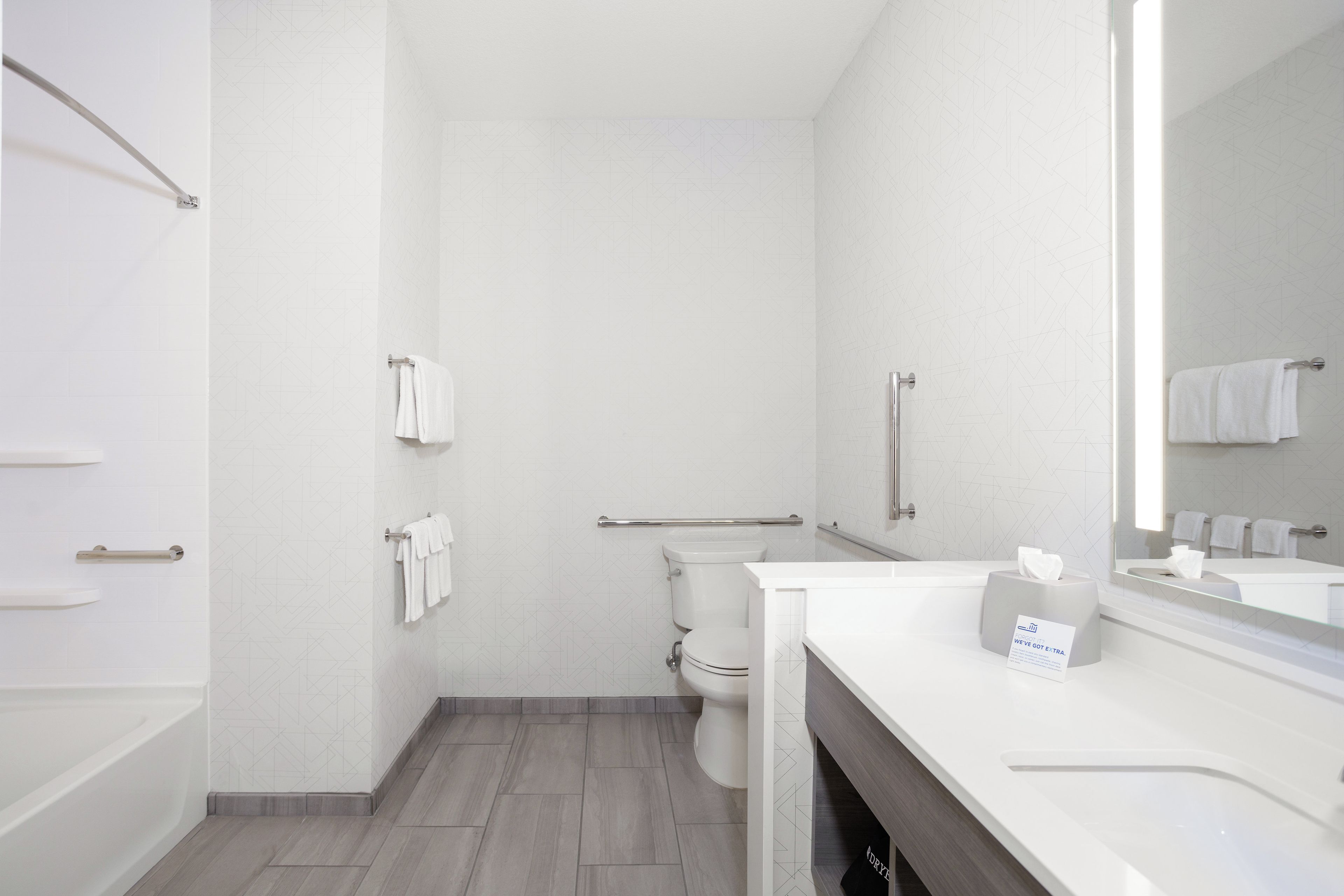 Un baño moderno con ducha, inodoro y tocador con espejo.