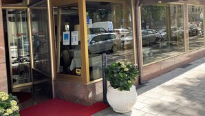 Entrada de un hotel con alfombra roja, ventanas amplias y un letrero que dice HOTEL KRAFT.