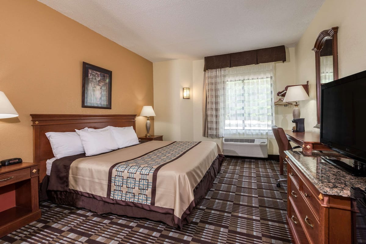 Una habitación de hotel con una cama, televisión, escritorio y aire acondicionado.