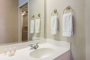 A bathroom with a white sink, two towel rings, and a mirror reflecting the room. - Days Inn by Wyndham Yadkinville (Yadkinville)