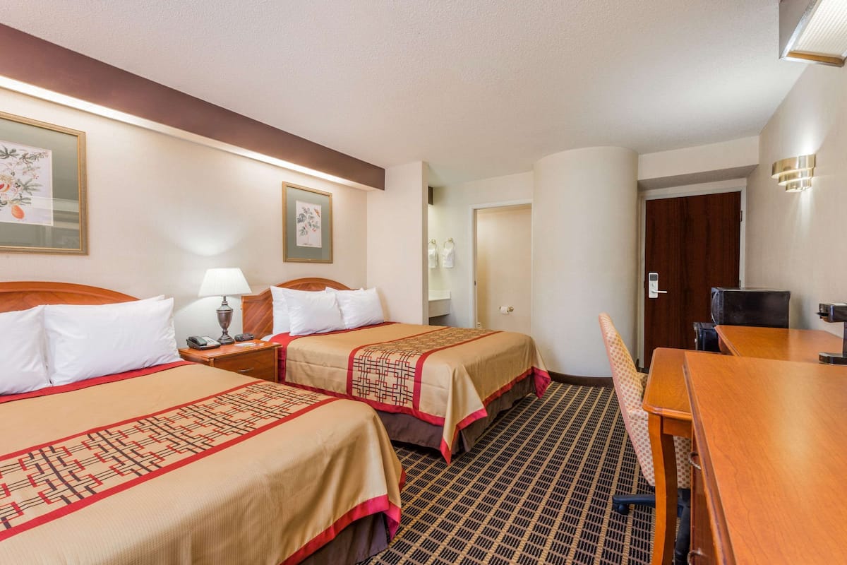 Habitación de hotel con dos camas, un escritorio y una silla.