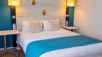 A hotel room with a bed, two bedside tables, and two wall-mounted lamps.