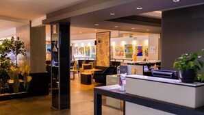 A modern hotel lobby with a reception desk, seating area, and art on the walls. - Mercure Lorient Centre Hotel (Lorient)