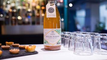 A bottle of Jus de Pomme Fermiere on a bar counter with glasses and pastries.