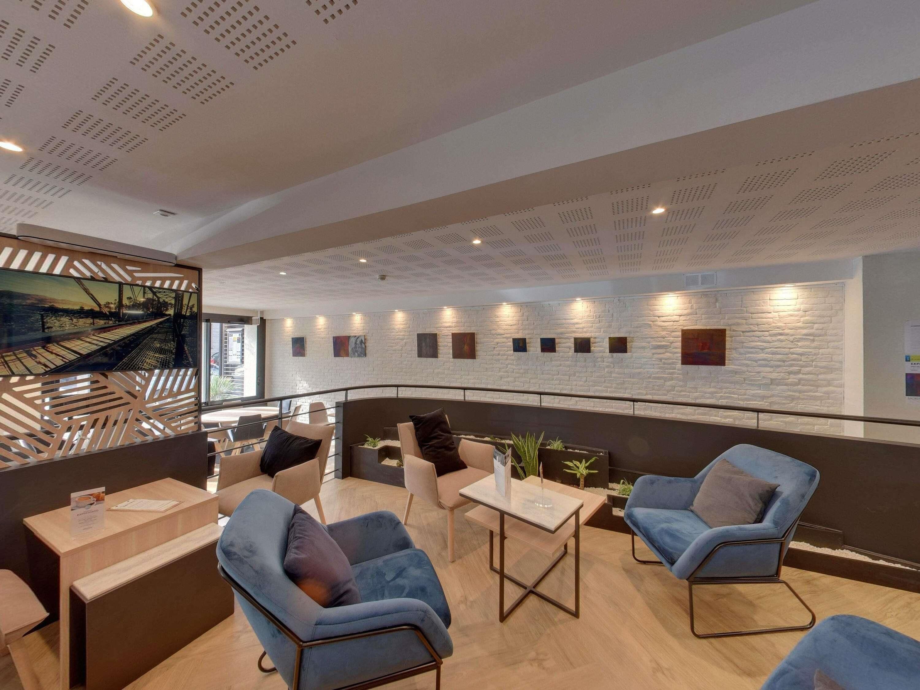 A modern lounge area with seating, a view of a bridge, and a white brick wall with artwork.