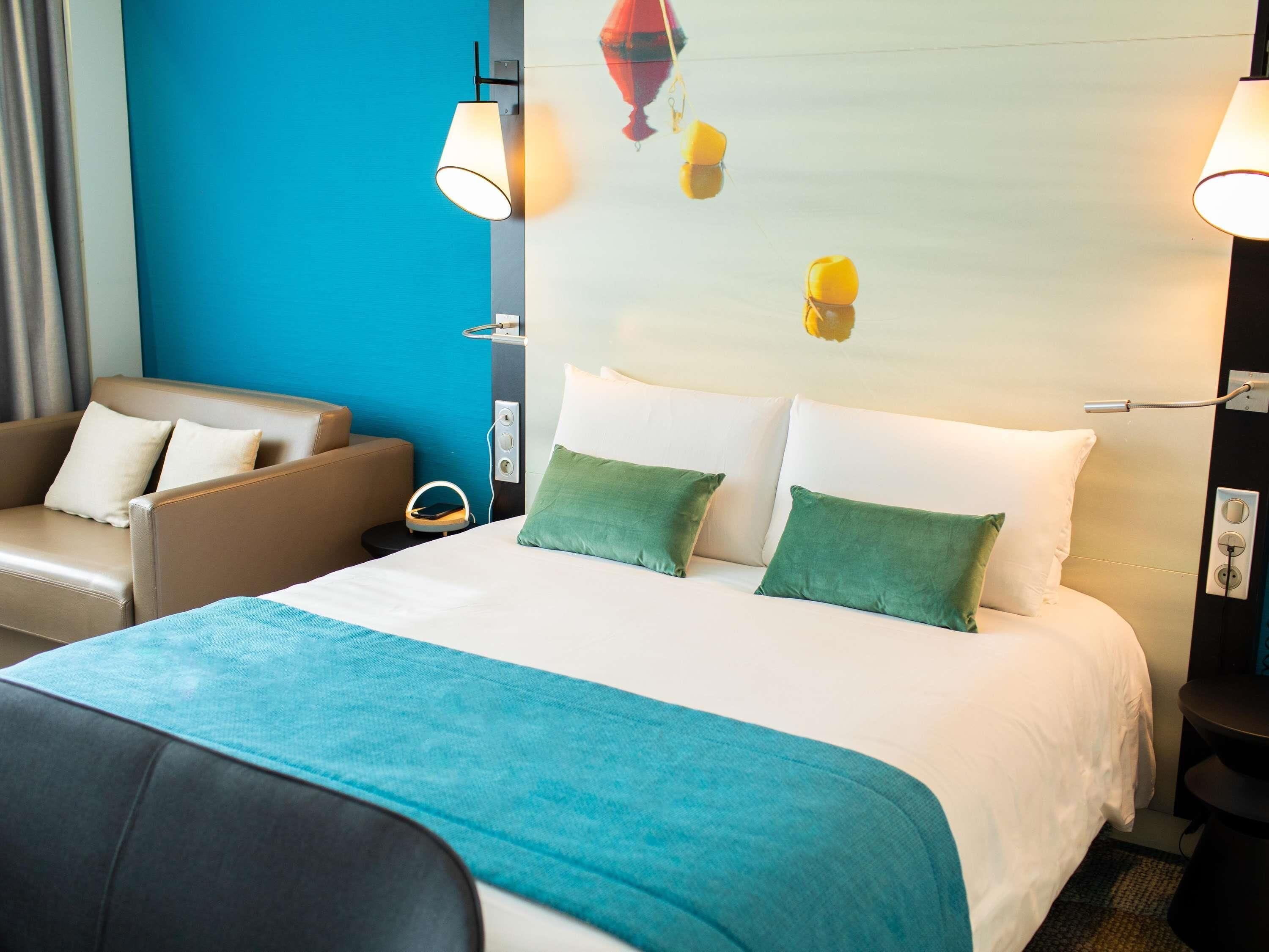 Ein Hotelzimmer mit Bett, einer Couch und einer Wandlampe.