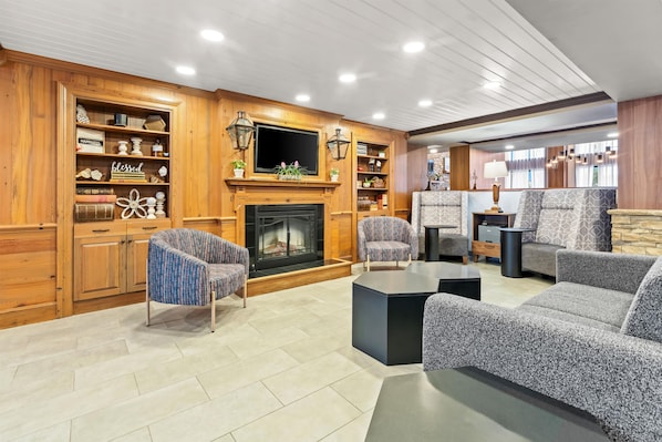 A living room with a fireplace, wooden bookshelves, and patterned furniture.