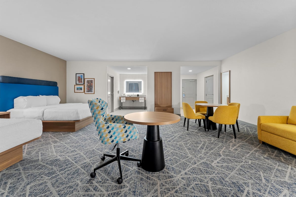 Ein Hotelzimmer mit Bett, Schreibtisch, Stuhl, Esstisch und einer Sitzecke.