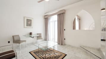 A modern living room with a glass coffee table, a sofa, a chair, and a ceiling fan.