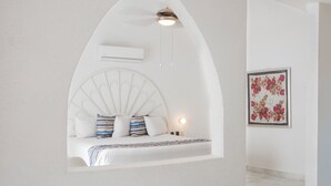 Une chambre à coucher dotée d’un plafond en arc unique, d’un lit agrémenté d’oreillers à rayures, d’un climatiseur fixé au mur et d’une œuvre d’art florale encadrée accrochée au mur.