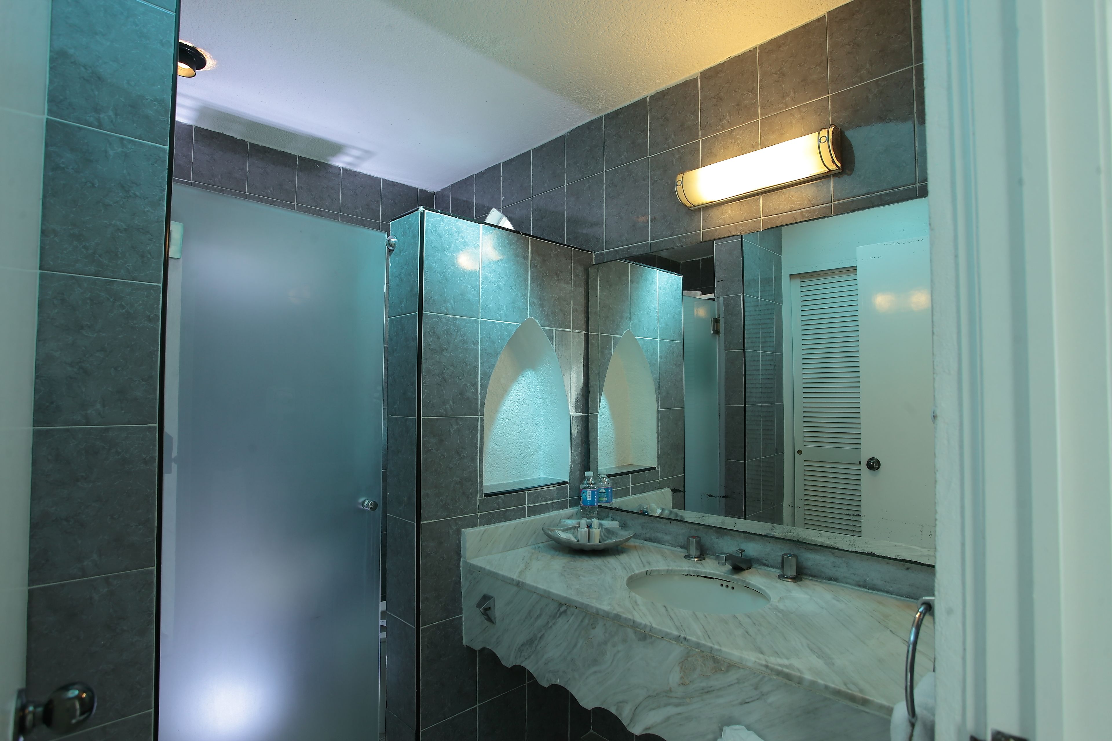 Une salle de bain dotée d’une douche à parois de verre, d’un lavabo en marbre et d’un grand miroir.
