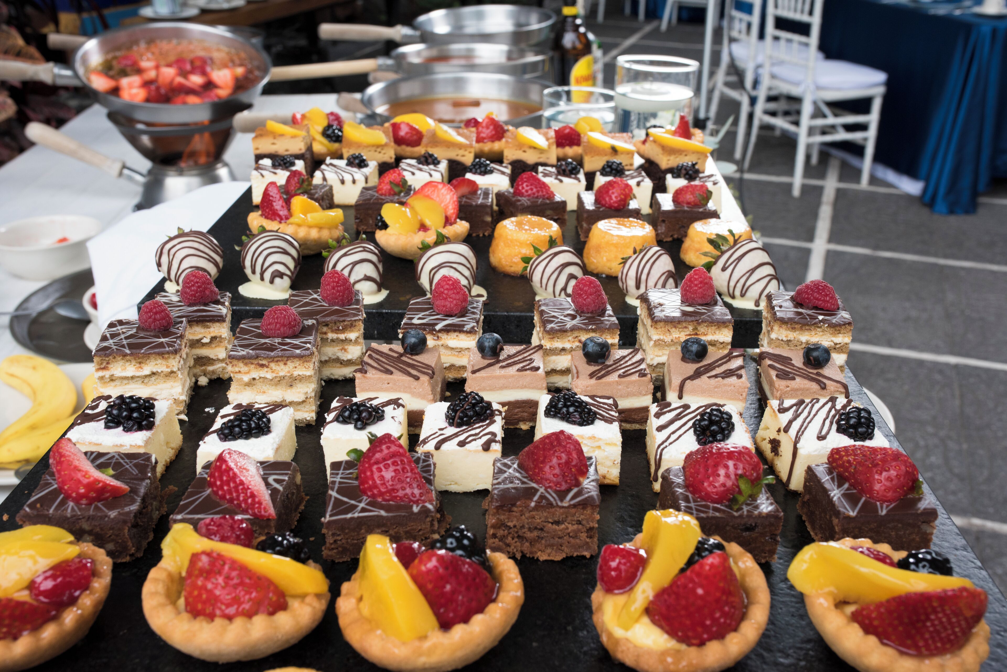 A variety of desserts arranged on a table, including tarts, cakes, and other sweet treats.