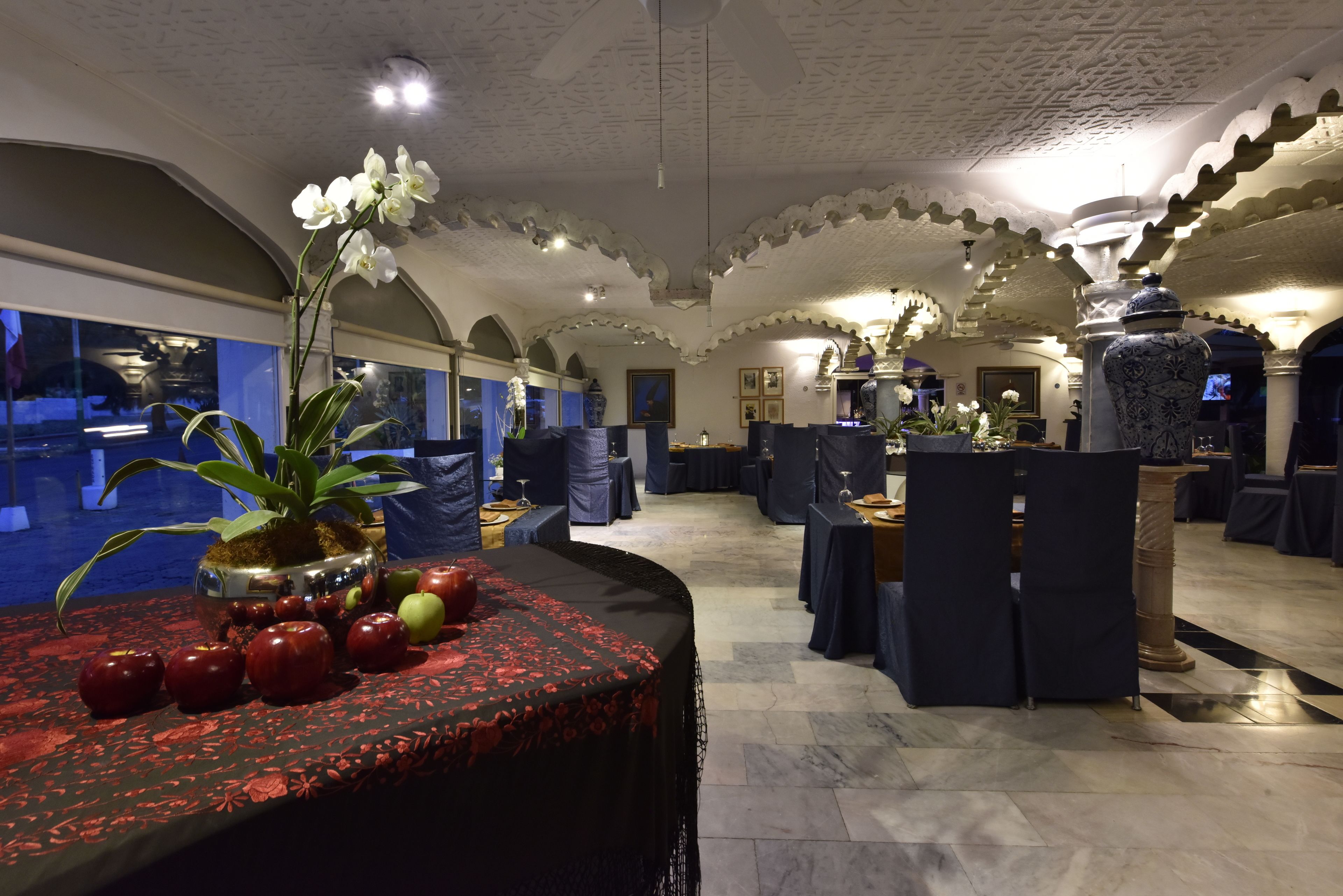 Un comedor espacioso con techos altos y arcos, con mesas dispuestas para comer y una decoración central.