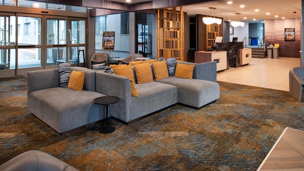 A modern lobby with a sectional sofa, a reception desk, and a large window. - La Quinta Inn & Suites by Wyndham Seattle Sea-Tac Airport (SeaTac)