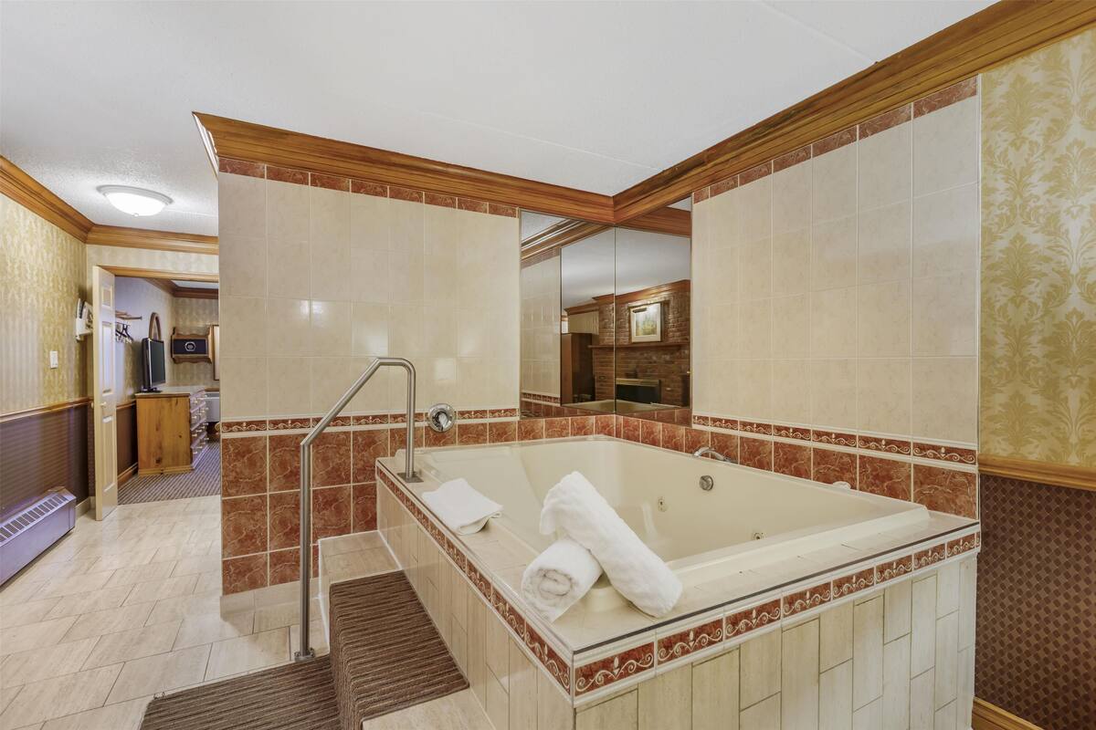 A bathroom with a large bathtub, a shower, and a vanity with a mirror.