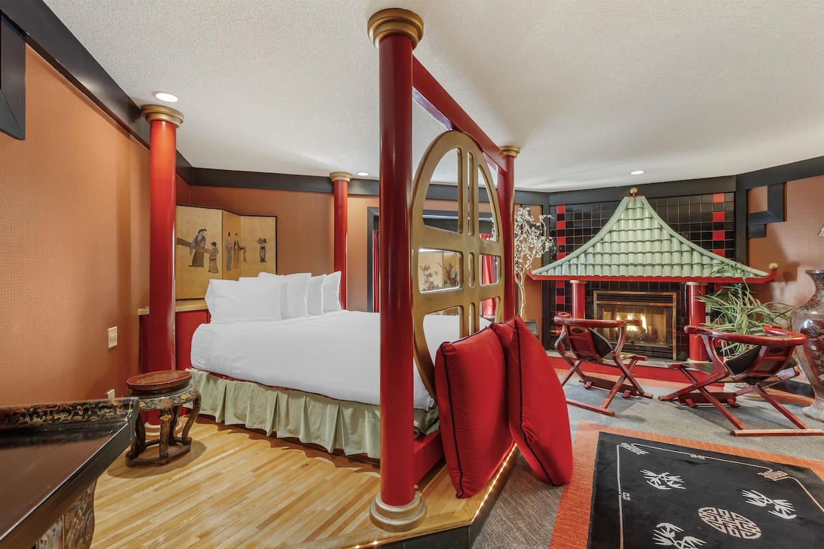 A hotel room with a bed, a small table, a chair, and a decorative wall piece.