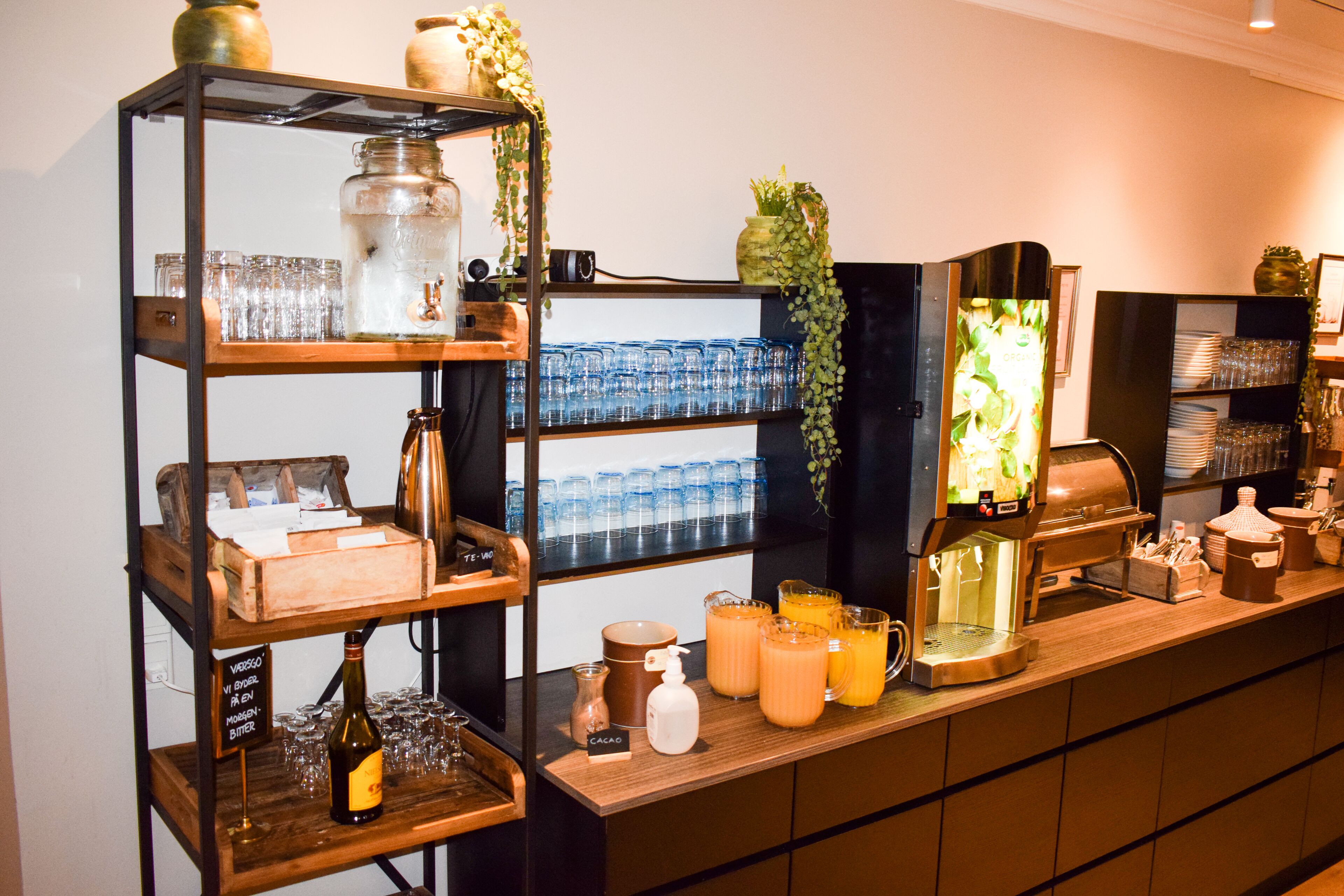 Un espace bar avec des étagères remplies de verres, une machine à café et diverses bouteilles.