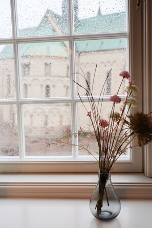 Se ve claramente una ventana con un jarrón de flores secas en el alféizar.