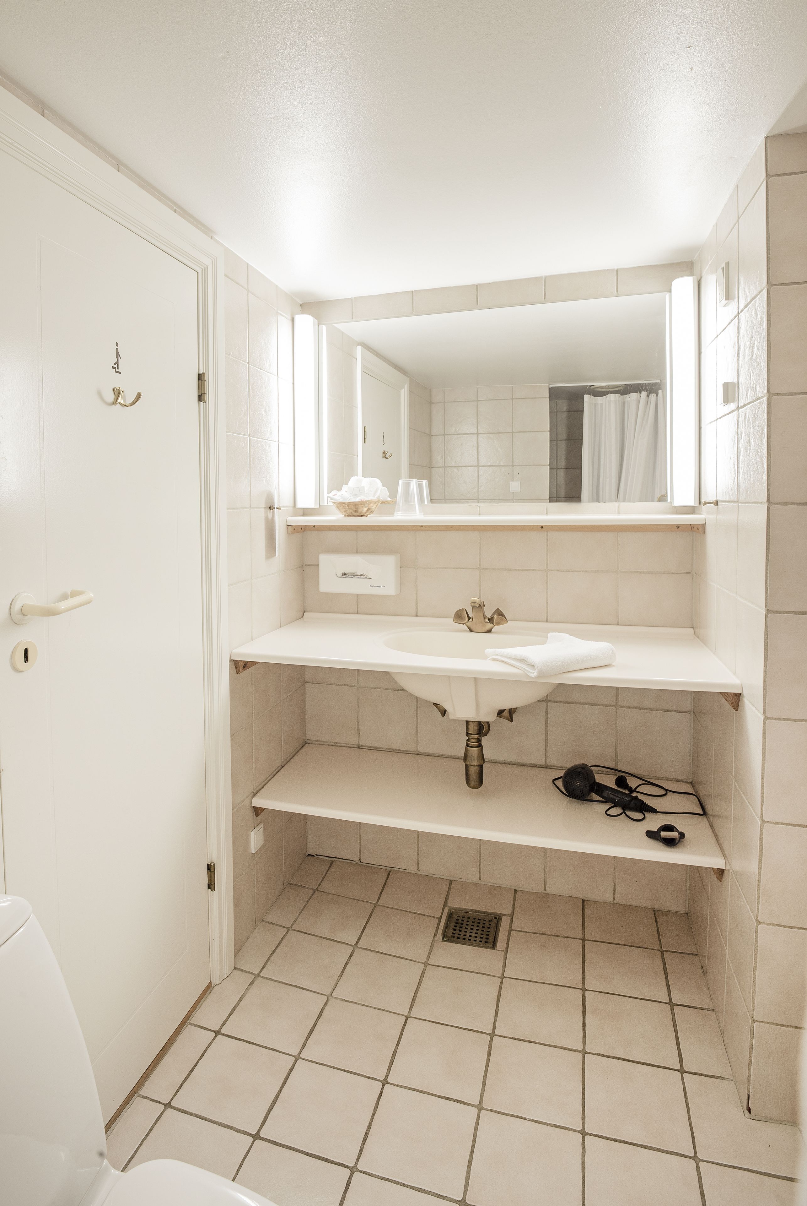 A bathroom with a white sink, mirror, and tiled floor.